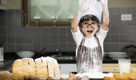 young child in a chef's hat baking bread