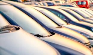 A row of parked cars on a public dealership at sunset.