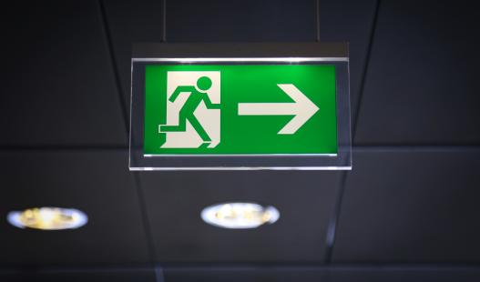 Green Emergency Exit sign with arrow and running stick figure man.