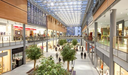 Photo of a modern three story shopping mall with a glass ceiling.