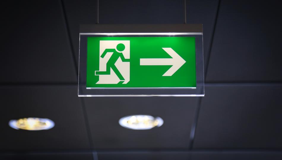 Green Emergency Exit sign with arrow and running stick figure man.