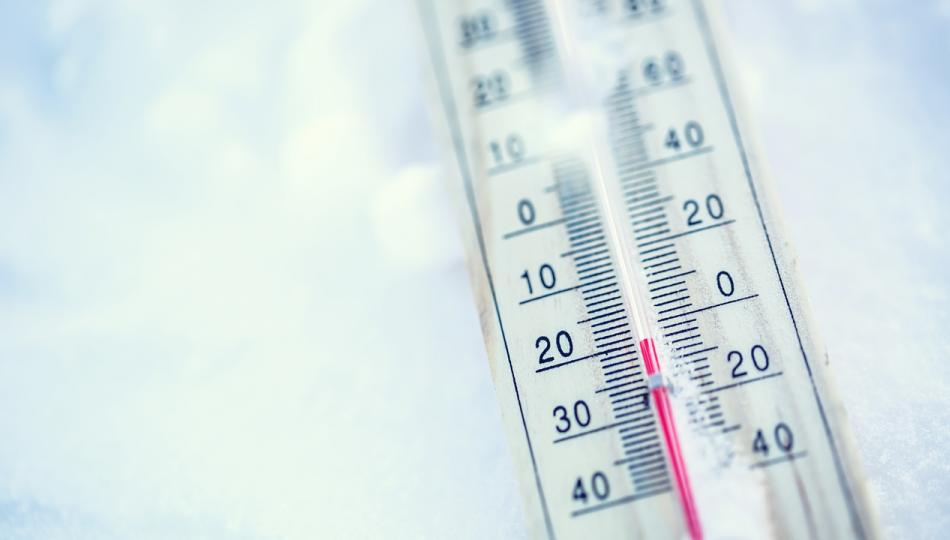 Close-up of a thermometer laying on the snow, with the temperature just below zero.