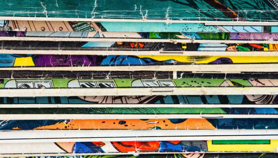 The spines of a stack of vintage comic books, laying in a horizontal stack.