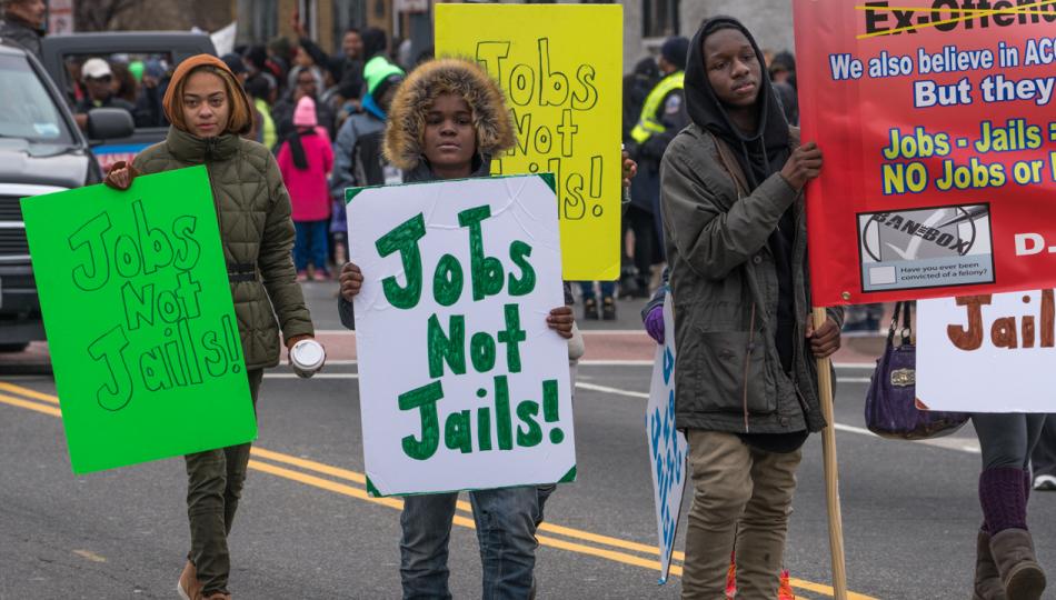 Young people waving Jobs Not Jails! signs march at a Martin Luther King, Jr. Day Peace Walk and Parade.