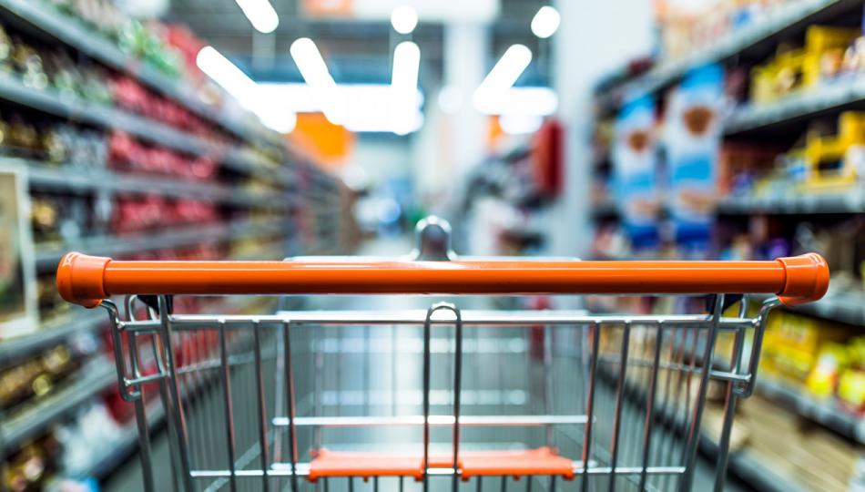 View of an empty shopping cart as seen from the perspective of the shopper, with the aisle blurred.