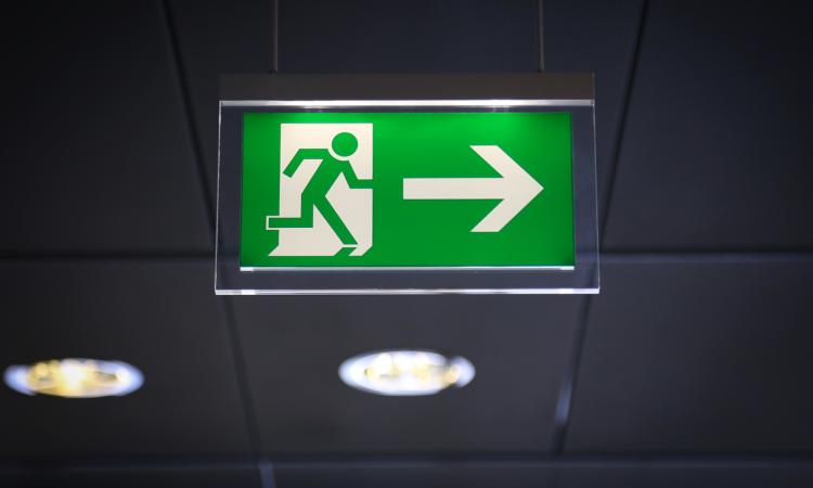 Green Emergency Exit sign with arrow and running stick figure man.