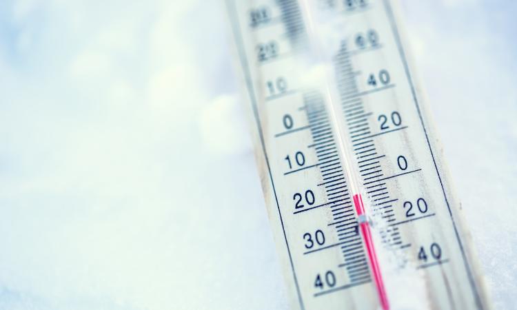 Close-up of a thermometer laying on the snow, with the temperature just below zero.