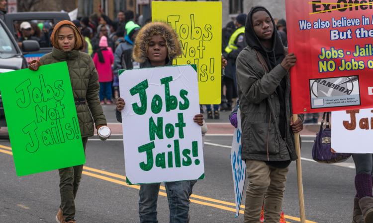 Young people waving Jobs Not Jails! signs march at a Martin Luther King, Jr. Day Peace Walk and Parade.