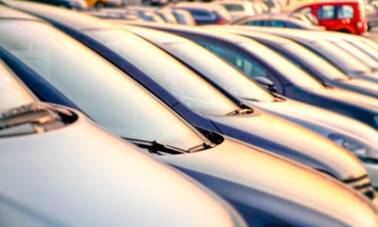 A row of parked cars at a dealership at sunset.