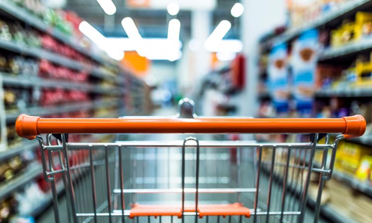 View of an empty shopping cart as seen from the perspective of the shopper, with the aisle blurred.