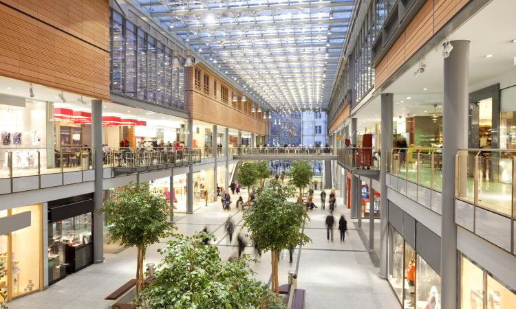 Photo of a modern three story shopping mall with a glass ceiling.