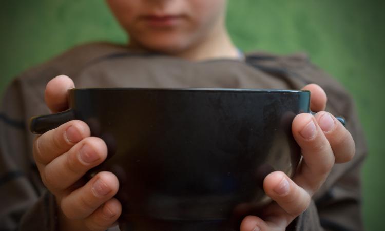 Hands of a child holding an empty bowl