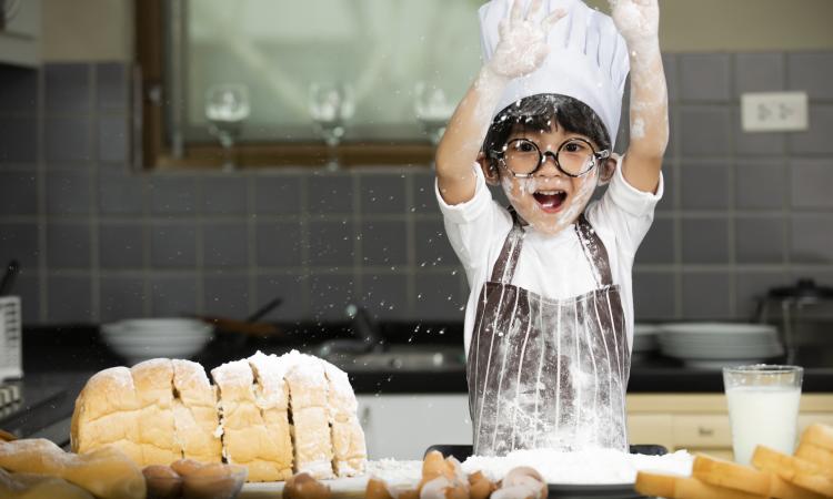young child in a chef's hat baking bread