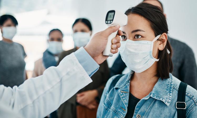 A woman wearing a mask and getting her temperature checked