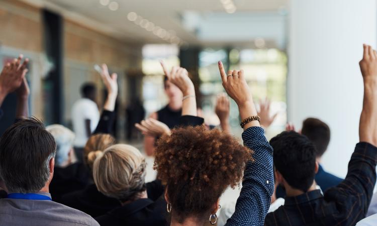 A group of people in a room raising their hands to vote