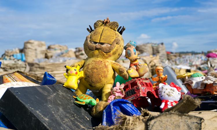 An abandoned dirty Garfield and other toys at a landfill