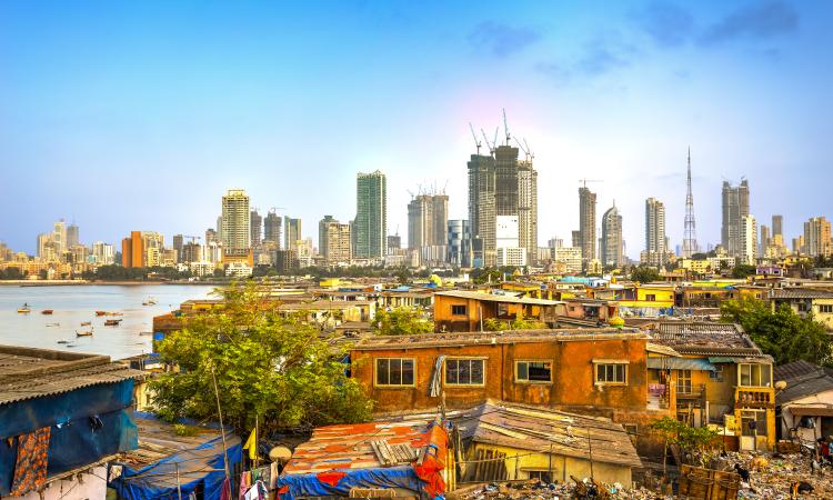 Photograph of Mumbai City, India, showing new construction of skyscrapers in the background and makeshift homes in the foreground.