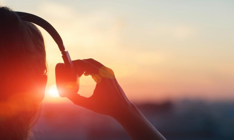 person wearing headphones and holding one side of them away from their ear