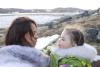 An Inuit mother and her daughter on the tundra of Baffin Island in late spring. They are interacting with each other. Background is rock, ice and distant mountains.